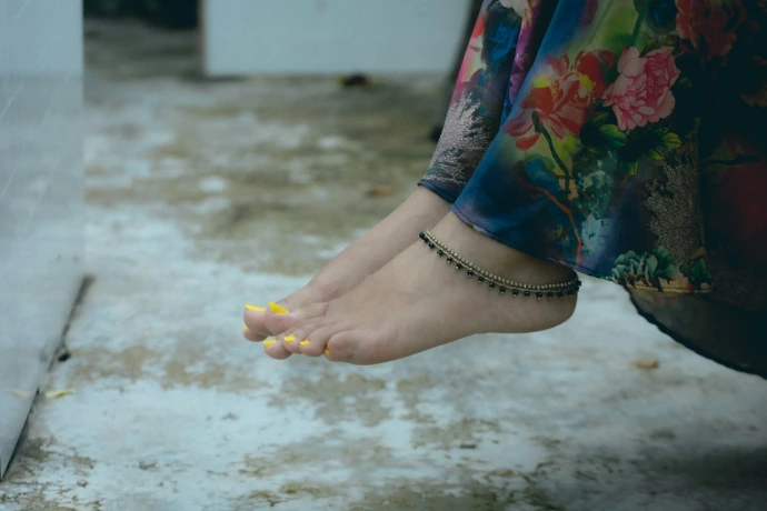 Woman's feet with yellow toenails and anklet